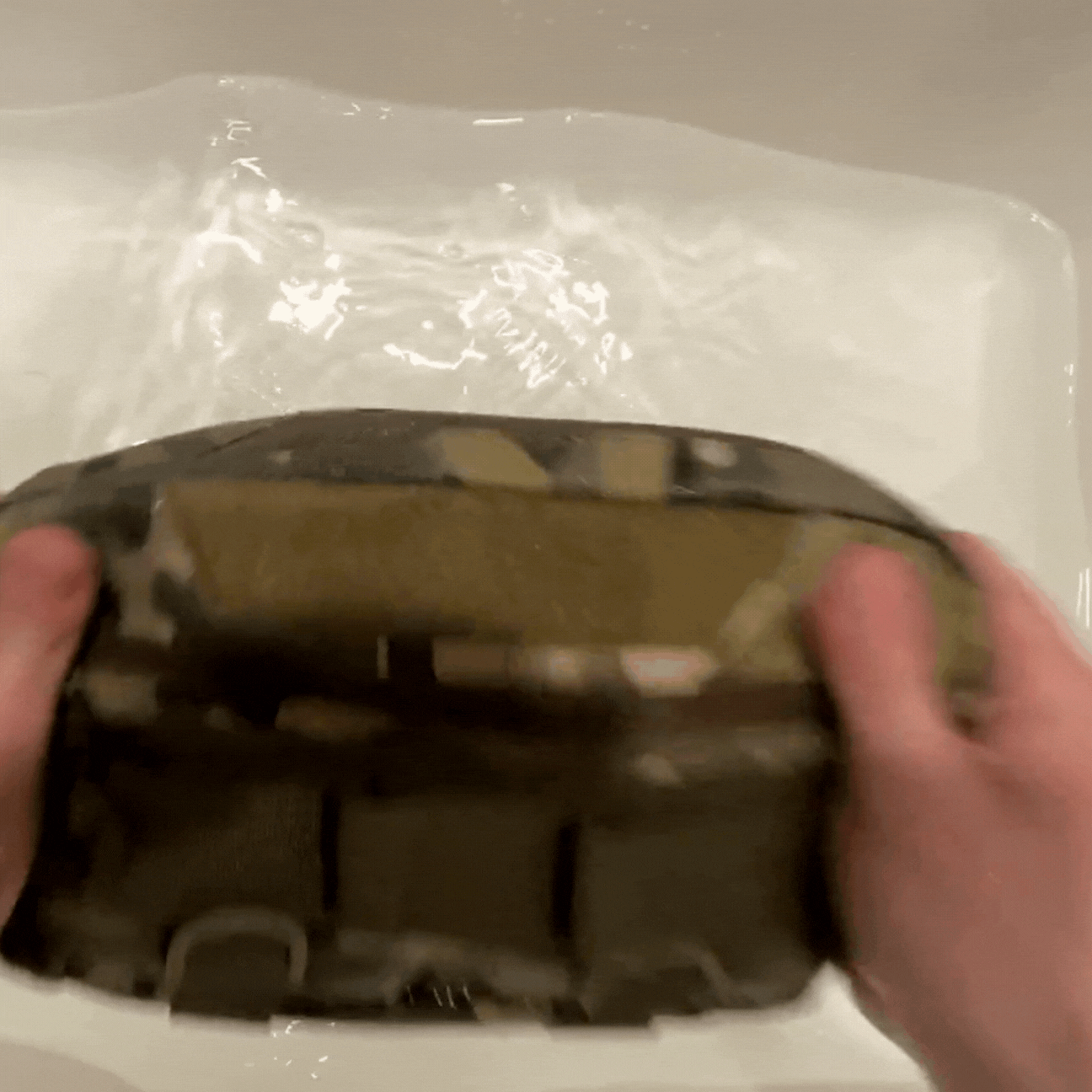 GIF showing man submerging tactical chest bag in water and pulling it out to demonstrate waterproof durability.